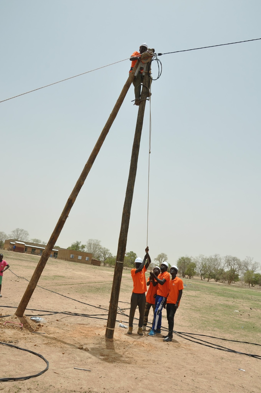 Des techniciens installent une ligne électrique dans une localité rurale au Sénégal